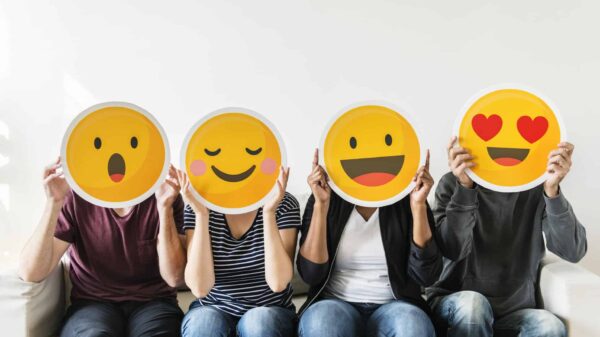 four people hold happy emoji masks