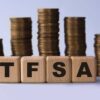 TFSA (Tax free savings account) acronym on wooden cubes on the background of stacks of coins