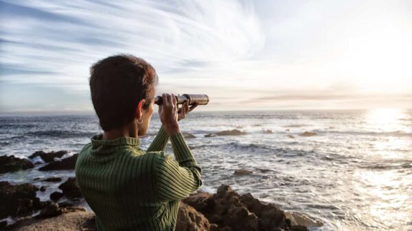 person with spyglass looks at ocean horizon